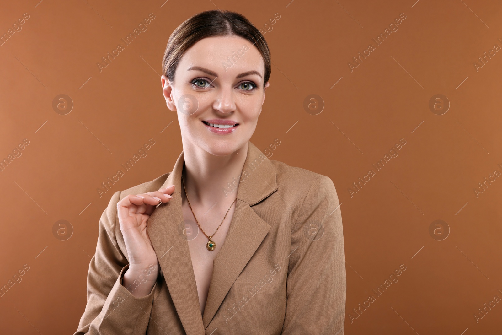 Photo of Beautiful woman with elegant necklace on brown background