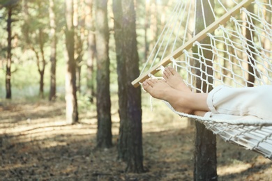 Woman resting in hammock outdoors on summer day, closeup of legs