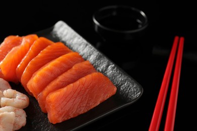 Photo of Delicious sashimi set of salmon and shrimps on black background, closeup