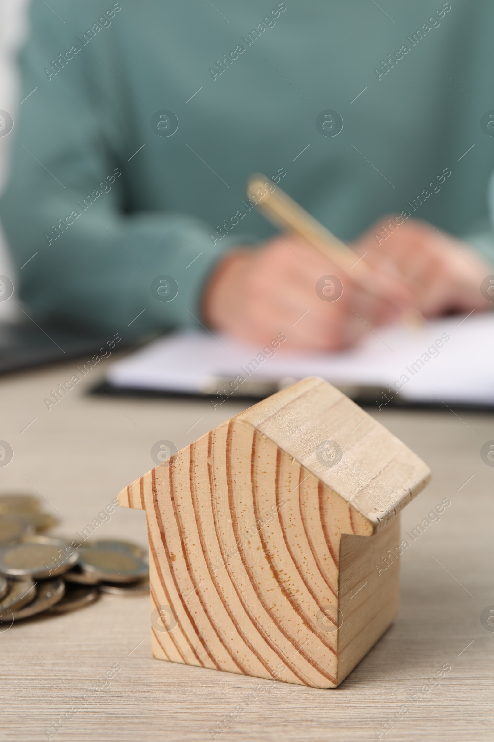 Photo of Woman planning budget at wooden table, focus on house model