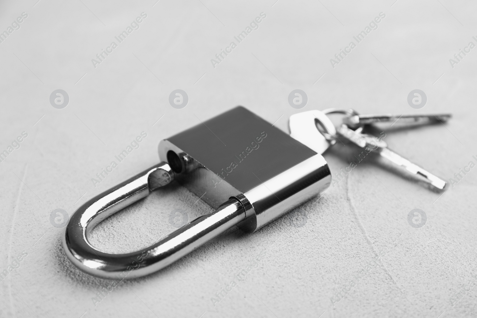 Photo of Modern padlock with keys on light table, closeup