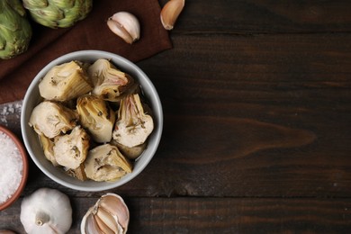 Photo of Pickled and fresh artichokes on wooden table, flat lay. Space for text