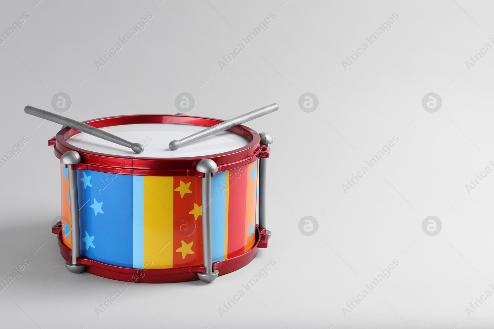 Photo of Colorful drum and sticks on light background, space for text. Percussion musical instrument