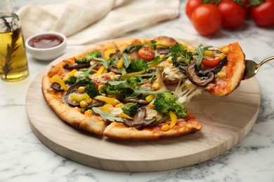 Photo of Taking piece of delicious vegetarian pizza at white marble table, closeup