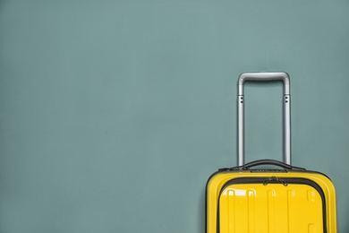 Photo of Packed bright yellow suitcase on color background