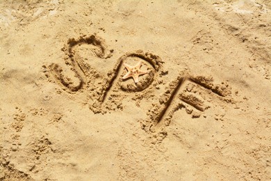 Abbreviation SPF written on sand and starfish at beach, above view