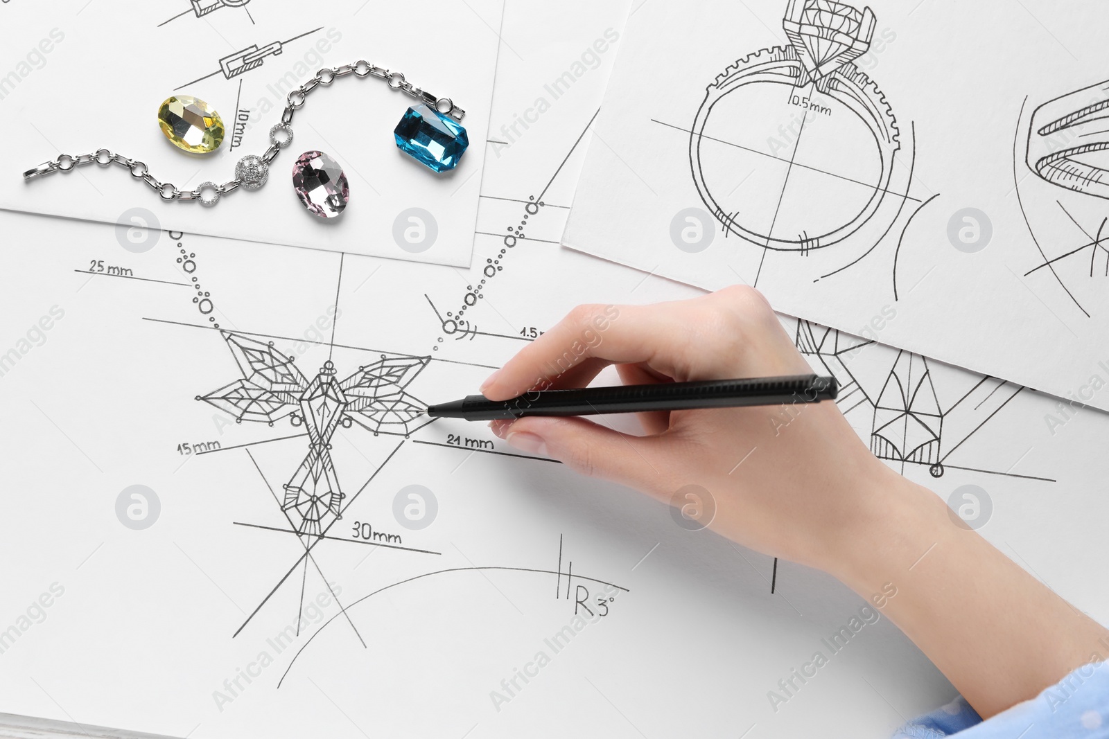 Photo of Jeweler drawing sketch of elegant necklace on paper, closeup