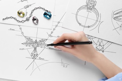 Photo of Jeweler drawing sketch of elegant necklace on paper, closeup