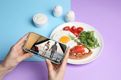 Woman watching video on mobile phone at table during breakfast, closeup