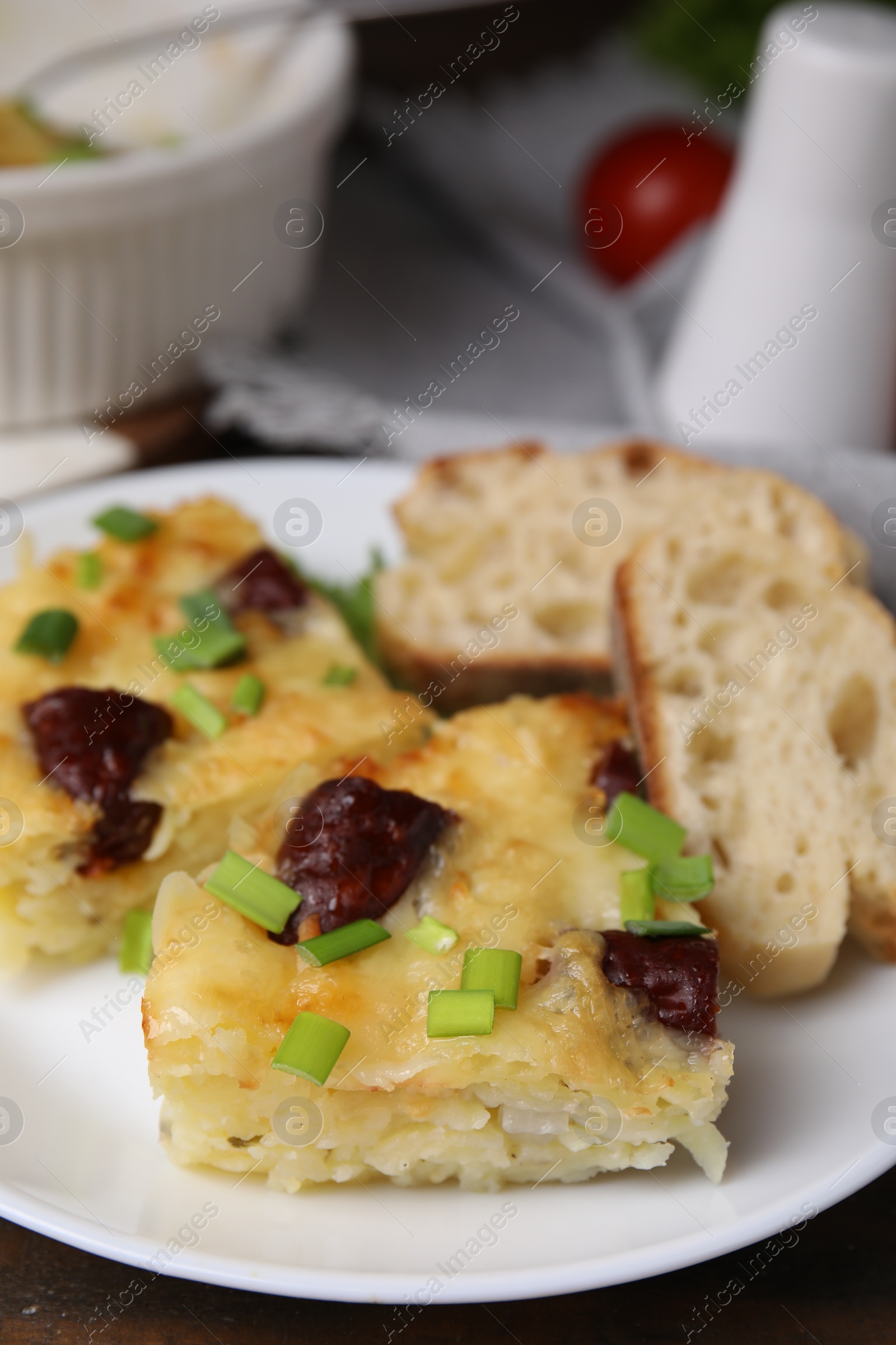 Photo of Tasty sausage casserole with green onion and bread on table, closeup