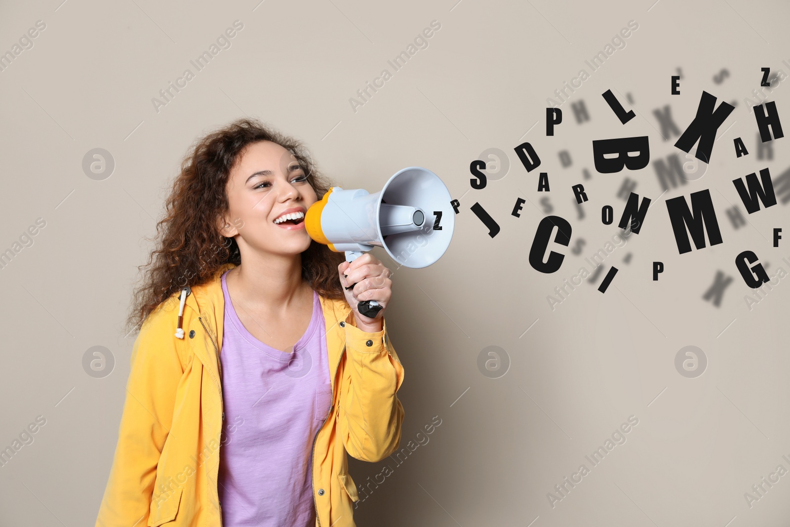 Image of Young African-American woman with megaphone and letters on light background. Speech therapy concept