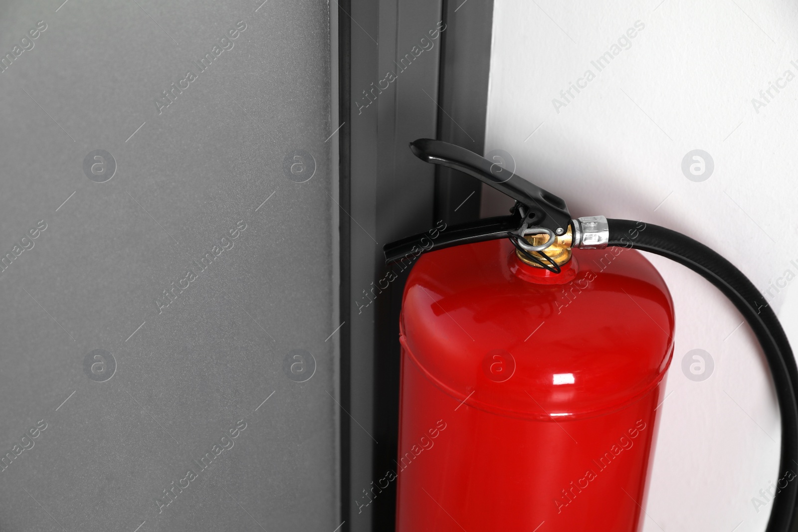 Photo of Fire extinguisher near door indoors, closeup. Space for text