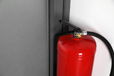 Photo of Fire extinguisher near door indoors, closeup. Space for text