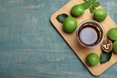 Photo of Delicious liqueur and fresh walnuts on light blue wooden table, top view. Space for text