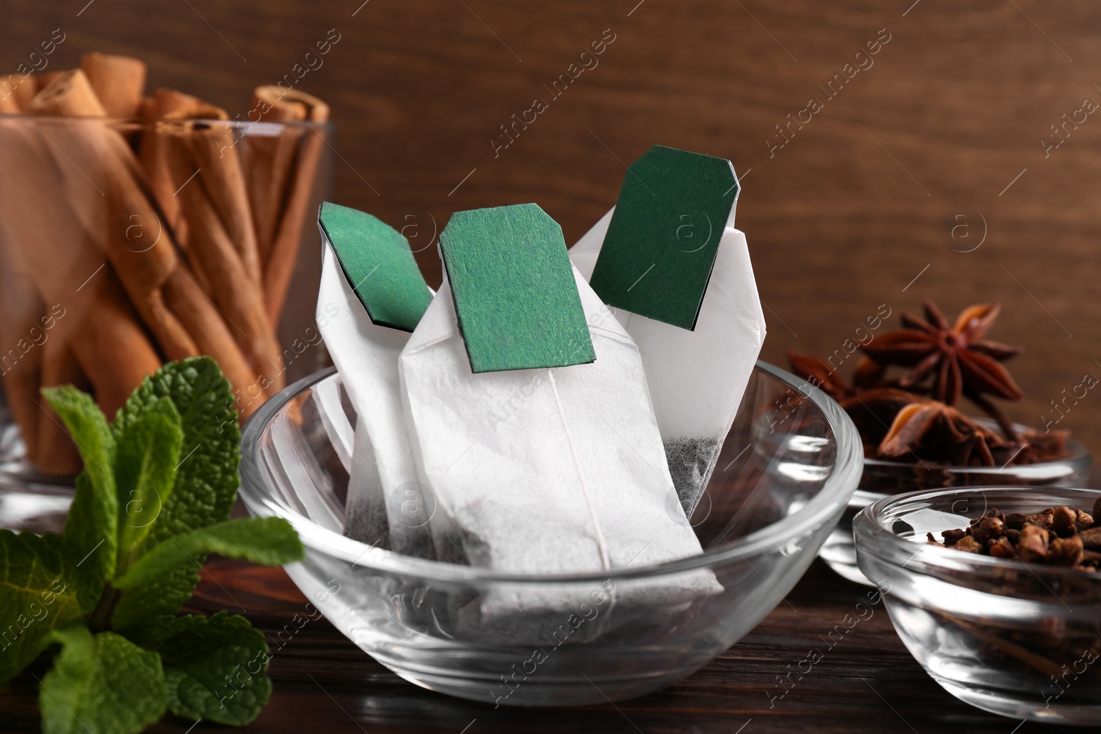 Photo of Tea bags and ingredients on wooden table, closeup