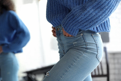 Photo of Woman wearing jeans near mirror indoors, closeup