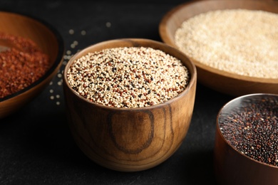 Bowls with different types of quinoa on black table