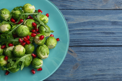 Tasty salad with Brussels sprouts on wooden table, top view. Space for text