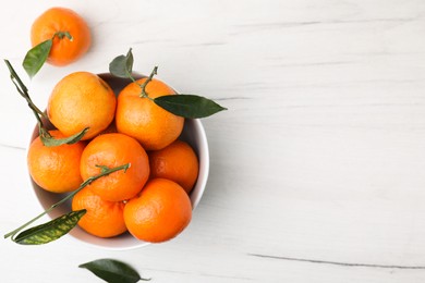 Photo of Bowl with fresh ripe tangerines and leaves on white wooden table, top view. Space for text