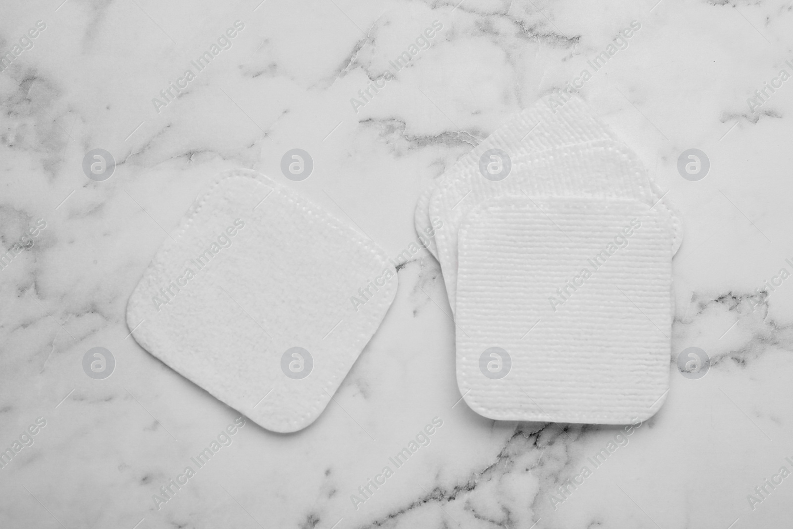 Photo of Clean cotton pads on white marble table, flat lay