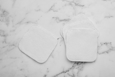 Photo of Clean cotton pads on white marble table, flat lay