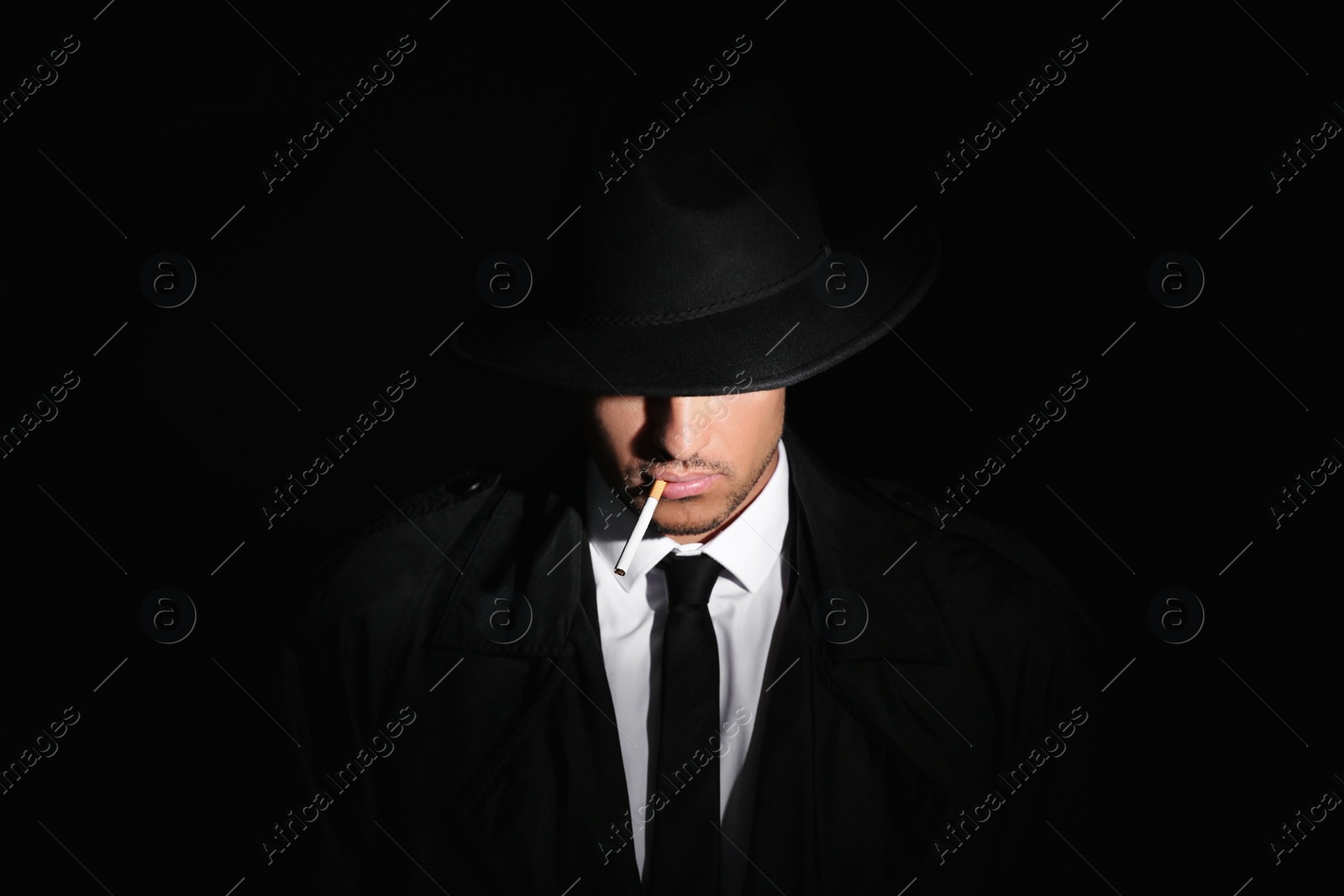 Photo of Private detective smoking cigarette on black background
