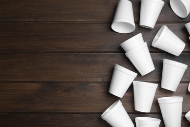Many white styrofoam cups on wooden table, flat lay. Space for text