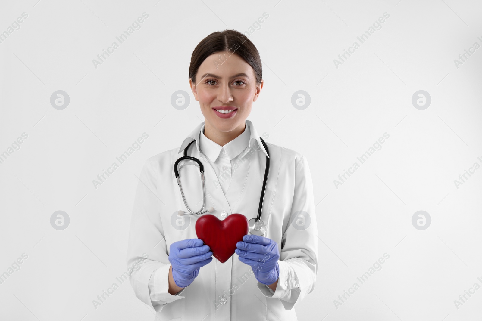 Photo of Doctor with stethoscope and red heart on white background. Cardiology concept