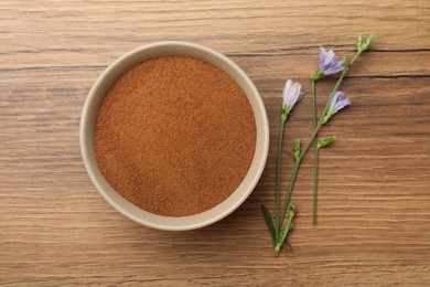 Photo of Bowl of chicory powder and flowers on wooden table, flat lay