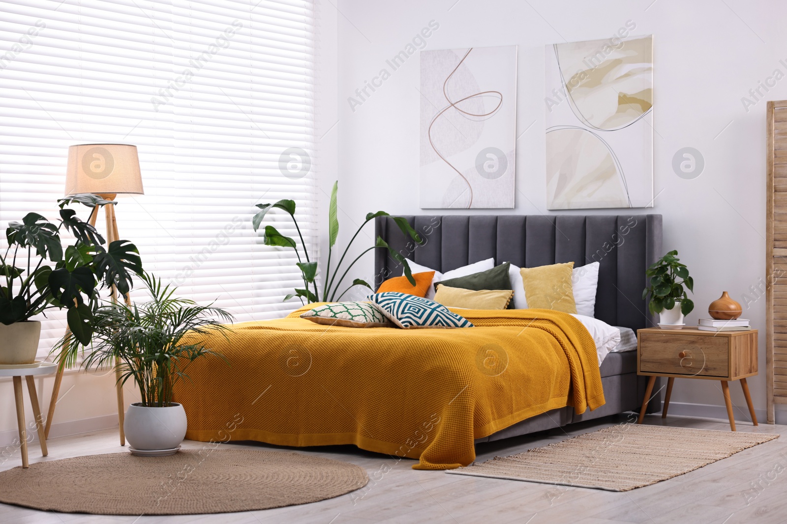 Photo of Bright plaid and colorful pillows on bed in stylish bedroom. Interior design