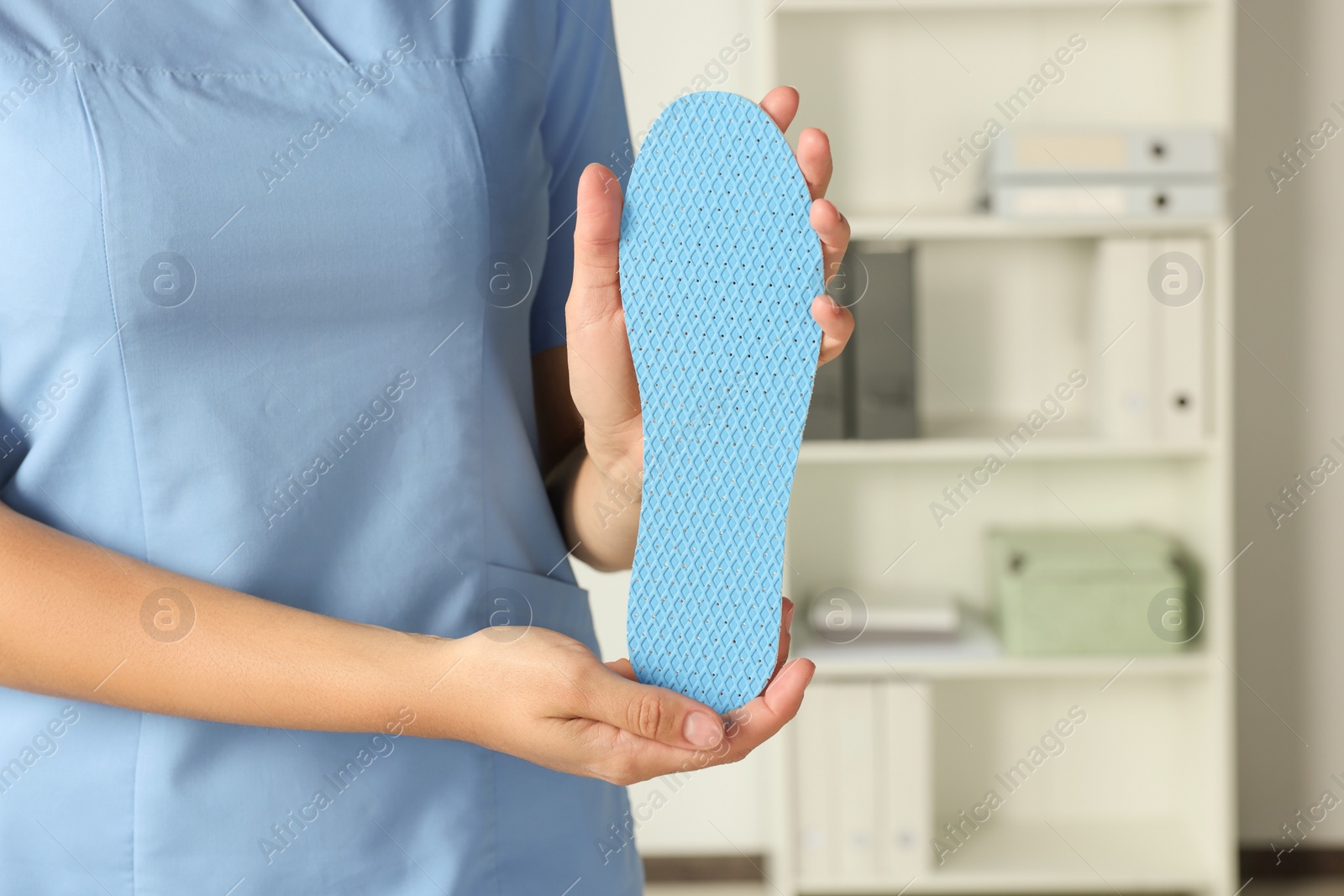 Photo of Female orthopedist showing insole in hospital, closeup