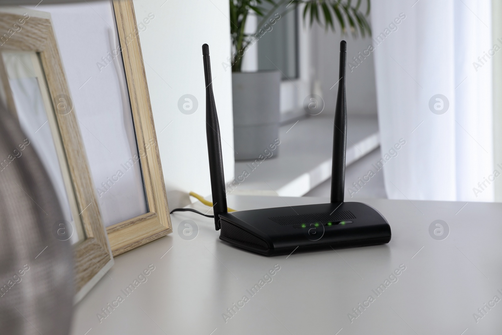 Photo of Modern Wi-Fi router on white table in room