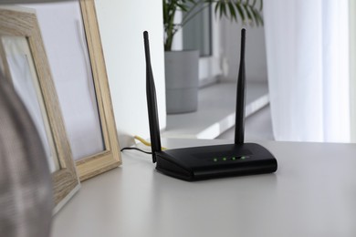 Photo of Modern Wi-Fi router on white table in room