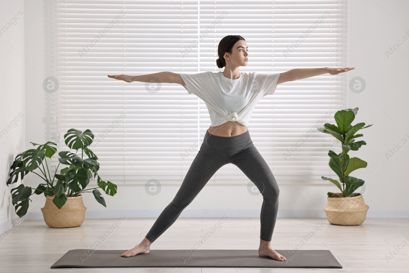 Photo of Girl practicing warrior asana in yoga studio. Virabhadrasana pose