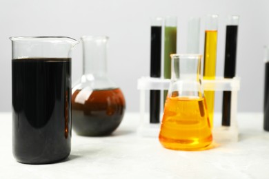 Photo of Laboratory glassware with different types of oil on white table