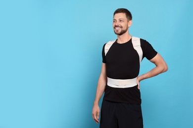 Photo of Handsome man with orthopedic corset on blue background, space for text