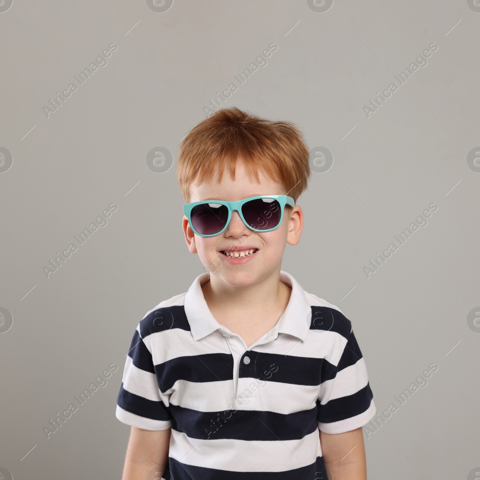 Photo of Cute little boy with sunglasses on light grey background