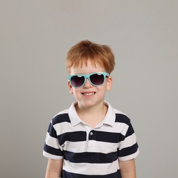 Photo of Cute little boy with sunglasses on light grey background