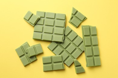 Photo of Pieces of tasty matcha chocolate bars on yellow background, top view
