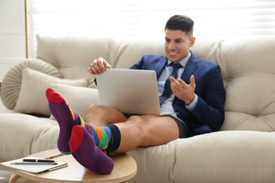 Businessman in jacket and underwear having video call at home, focus on legs