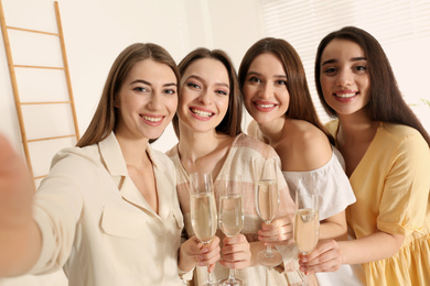 Photo of Beautiful young ladies with champagne taking selfie indoors. Woman's Day