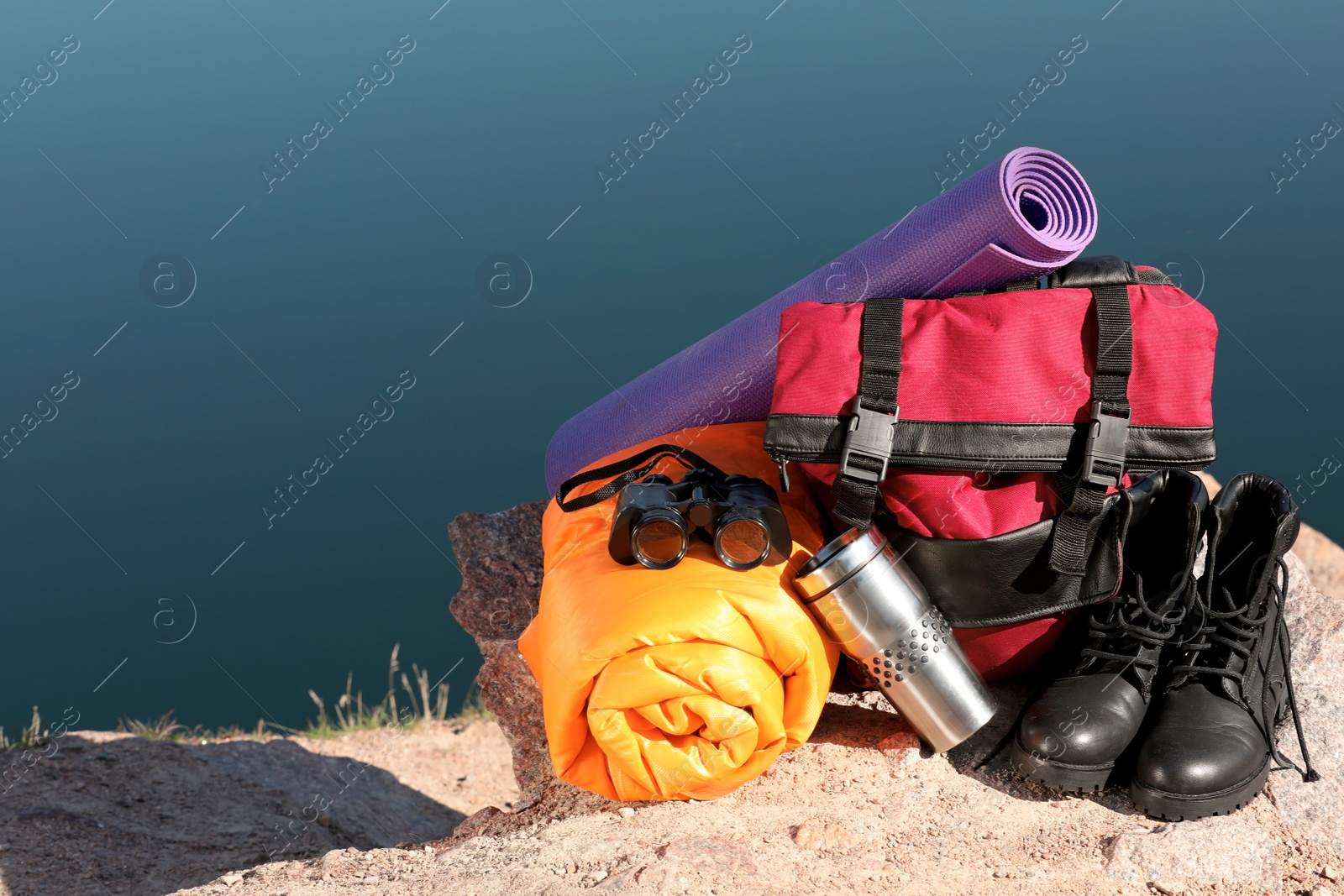 Photo of Set of camping equipment with sleeping bag on ground outdoors. Space for text
