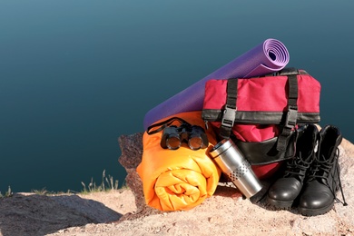 Set of camping equipment with sleeping bag on ground outdoors. Space for text