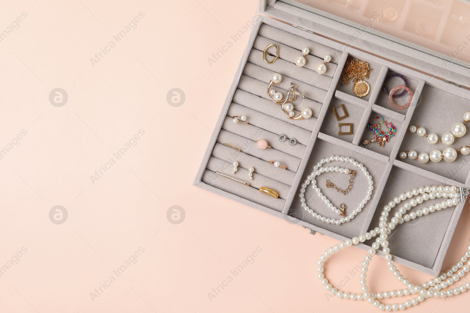 Photo of Jewelry box with many different accessories on beige background, top view. Space for text