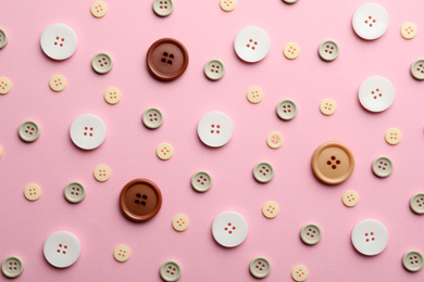 Photo of Different sewing buttons on pink background, flat lay