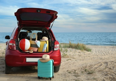 Photo of Red car luggage on beach, space for text. Summer vacation trip