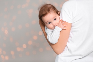 Young mother holding cute baby against  defocused lights. Space for text