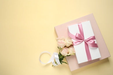 Photo of Elegant gift boxes and beautiful flowers on beige background, flat lay. Space for text