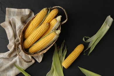 Photo of Corn cobs on black table, flat lay