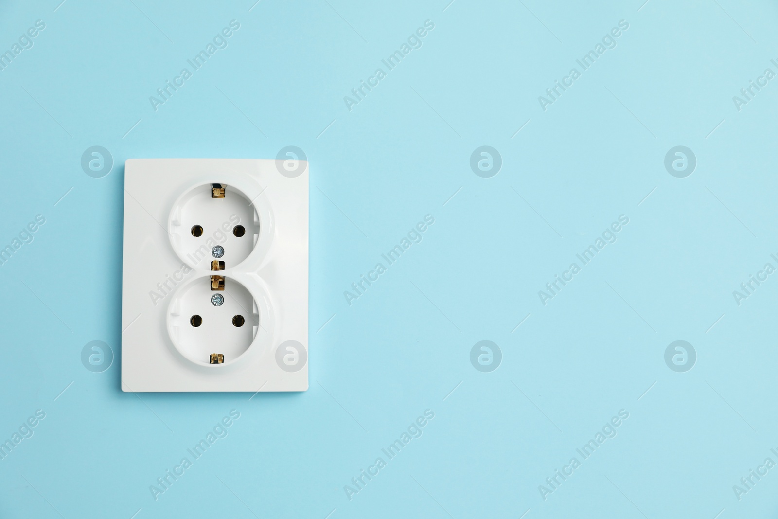 Photo of Double power socket on light blue wall, space for text. Electrical supply
